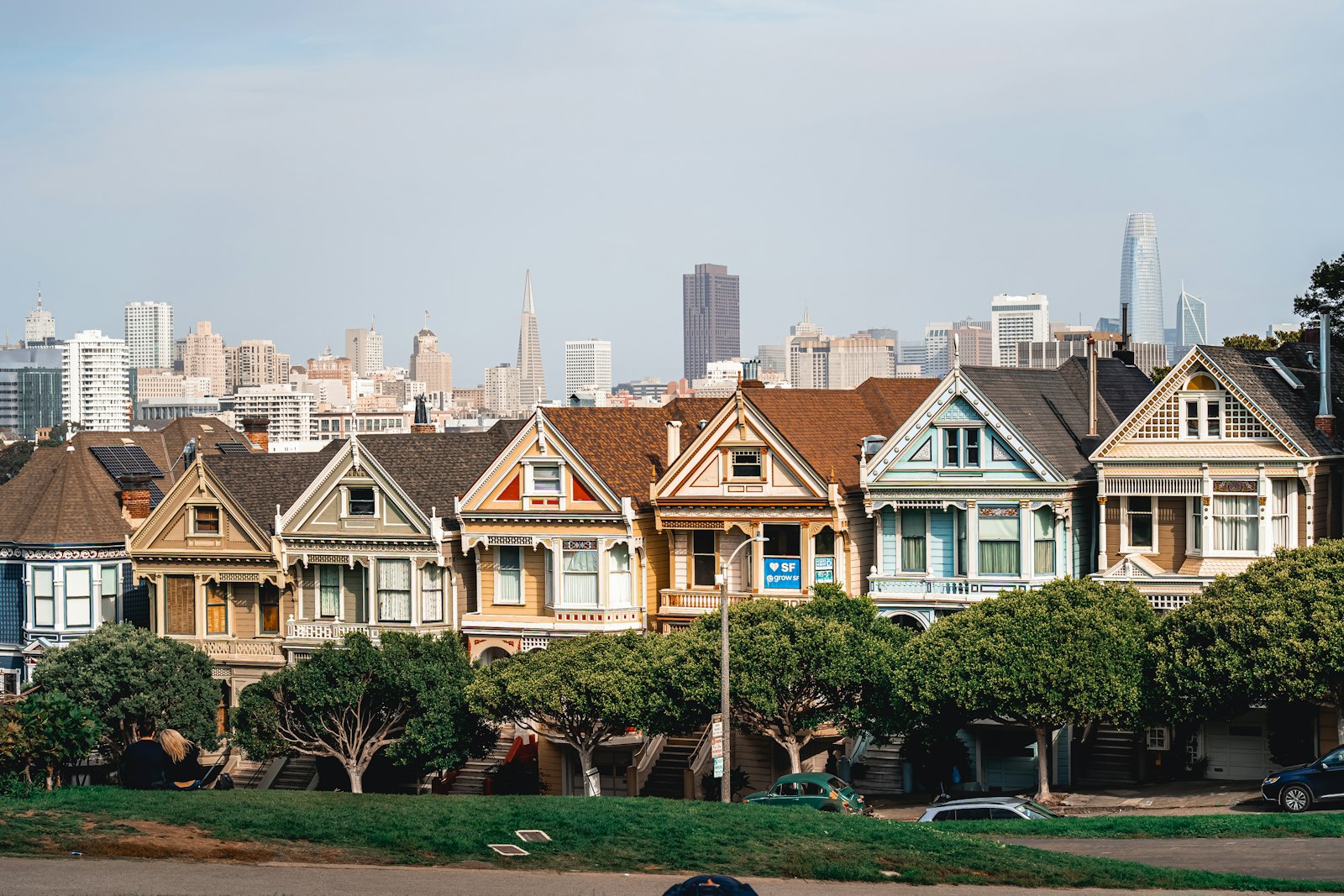 A row of Victorian houses in San Francisco with downtown towers in the background.